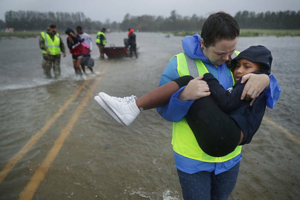 A volunteer from the Civilian Crisis Response Team carries a child out of the floodwaters in James City on Friday.