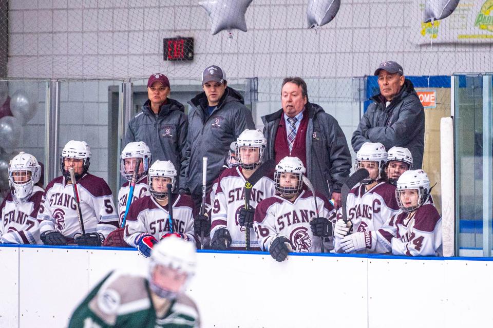 Bishop Stang Coach Bill Theodore and the bench watch the play on the ice.
