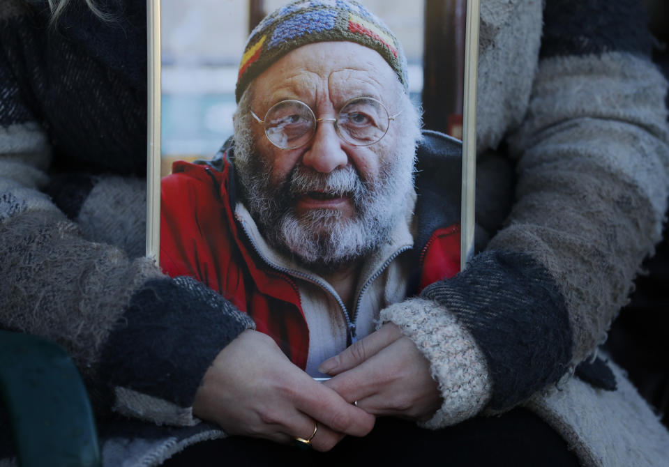 Jo Goodman holds a portrait of her late father Stuart as she poses for a photo in London, Friday, Jan. 22, 2021. Jo's father Stuart died of COVID-19, in April 2020. (AP Photo/Alastair Grant)