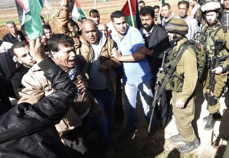 Palestinian minister Ziad Abu Ein (L) argues with Israeli soldiers during a protest near the West Bank city of Ramallah December 10, 2014. REUTERS/Mohamad Torokman