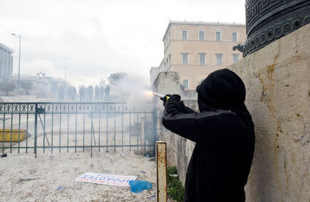 A protester shoots a smoke grenade at police officers during a demonstration against the agreement reached by Greece and Macedonia to resolve a dispute over the former Yugoslav republic's name, in Athens, Greece, January 20, 2019. REUTERS/Alexandros Avramidis