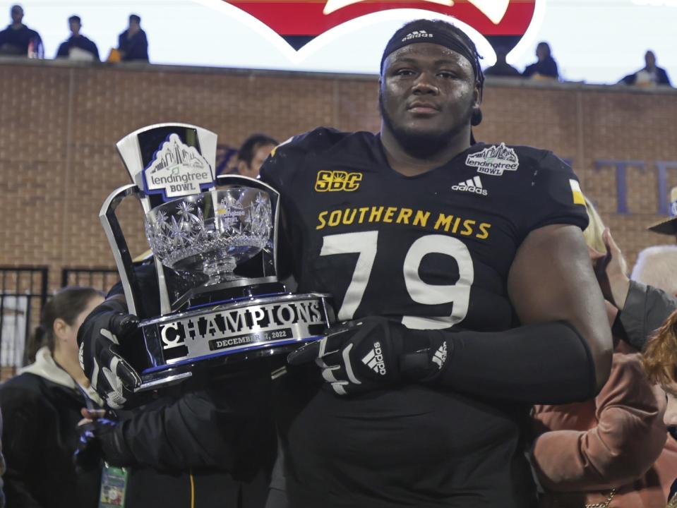 Dec 17, 2022; Mobile, AL, USA; Southern Miss Golden Eagles offensive lineman Tykeem Doss (79) poses with the Lending Tree Bowl Championship Trophy after defeating the Rice Owls in the Lending Tree Bowl at Hancock Whitney Stadium. Mandatory Credit: Robert McDuffie-USA TODAY Sports