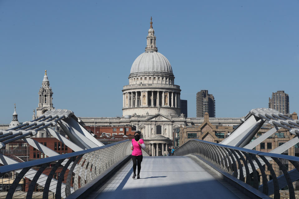 A jogger with their face covered crosses Millenium Bridge in London after Prime Minister Boris Johnson put the UK in lockdown to help curb the spread of the coronavirus. (Photo by Jonathan Brady/PA Images via Getty Images)