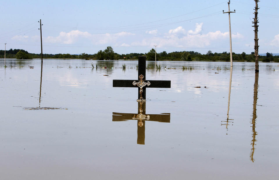 A cross is seen in floodwaters at a cemetery during heavy floods in the village of Vojskova