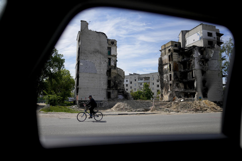 A man rides a bicycle in front of a building ruined by shelling in Borodyanka, on the outskirts of Kyiv, Ukraine, Wednesday, May 25, 2022. (AP Photo/Natacha Pisarenko)