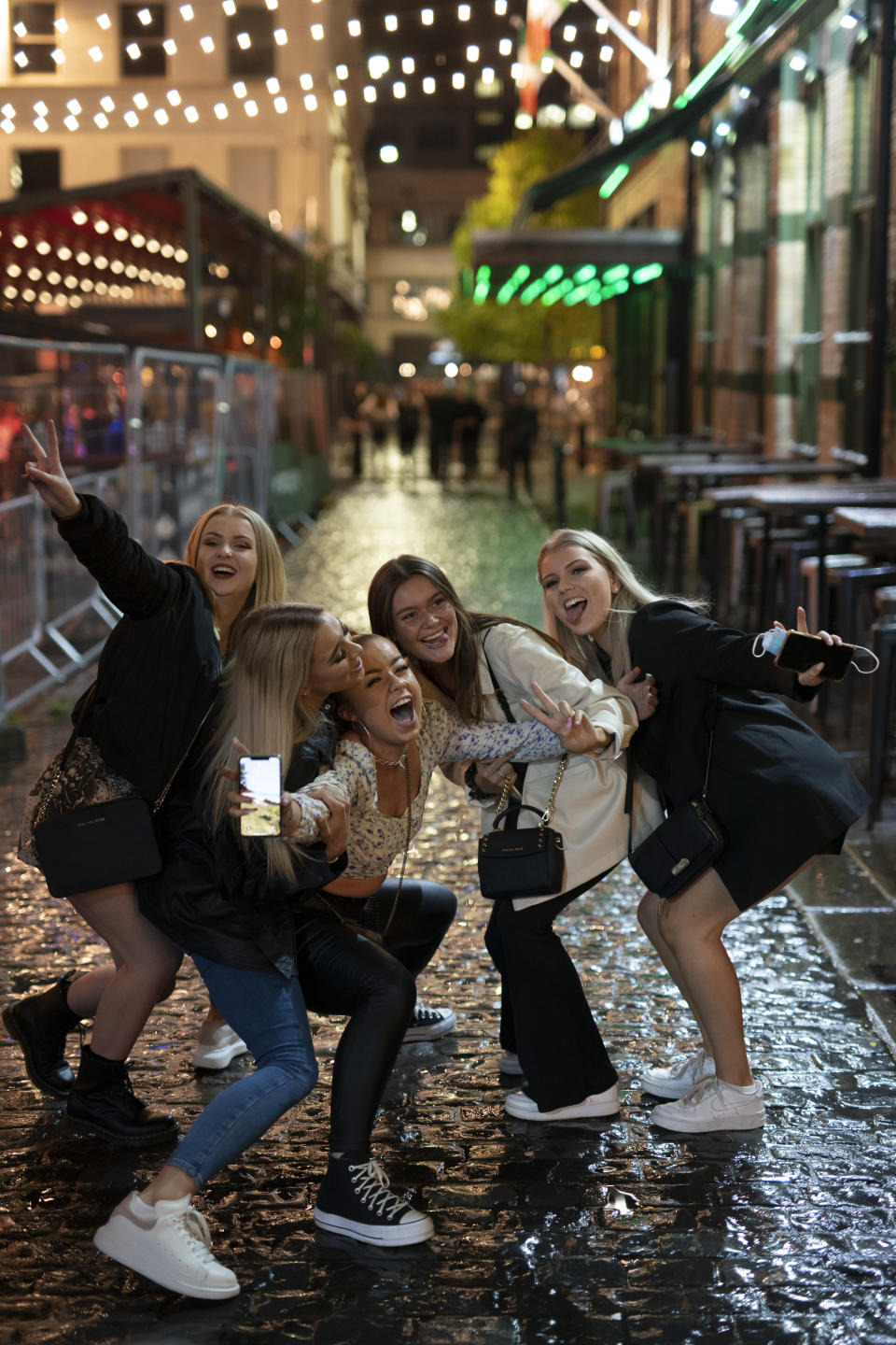 Young people pose for a photo, outside a bar in Liverpool after Prime Minister Boris Johnson laid out a new three-tier alert system for England, in Liverpool, England, Monday Oct. 12, 2020. The British government has carved England into three tiers of risk in a bid to slow the spread of a resurgent coronavirus. The northern city of Liverpool is in the highest category and will close pubs, gyms and betting shops. (AP Photo/Jon Super)