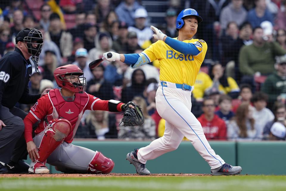 Boston Red Sox's Masataka Yoshida, right, follows through on an RBI single in front of Los Angeles Angels' Logan O'Hoppe, second from left, during the first inning of a baseball game, Saturday, April 13, 2024, in Boston. (AP Photo/Michael Dwyer)
