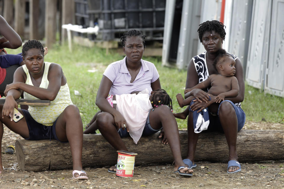 Women with children sit on a log at a migrant camp in Lajas Blancas, Darien province, Panama, Saturday, Aug. 29, 2020. Panama, a transit point for virtually every migrant heading from South America to the United States, closed its borders on March 16 to halt the spread of COVID-19. (AP Photo/Arnulfo Franco)