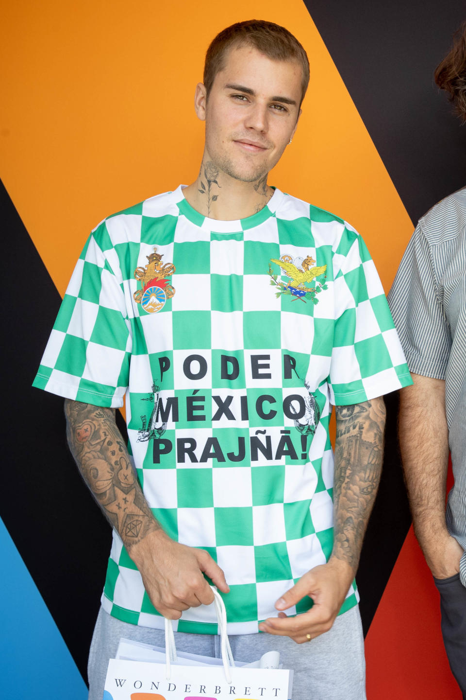 Justin has neck tats and a green checkered shirt