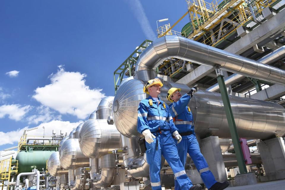 People in personal protective equipment walking through an industrial setting. 