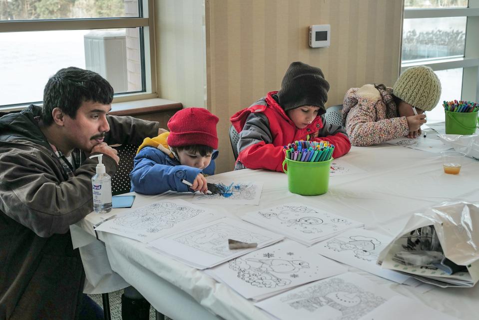 Isaac De Almeida from DeWitt waits patiently as his kids from left, Gus, 3, Johah, 7, and Brigit, 9, color in the kids area at MSU Federal Credit Union's 85th anniversary celebration Sunday, Nov. 20, 2022.