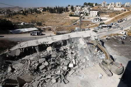 An Israeli military bulldozer demolishes a building near a military barrier in Sur Baher, a Palestinian village on the edge of East Jerusalem in an area that Israel captured and occupied in the 1967 Middle East War