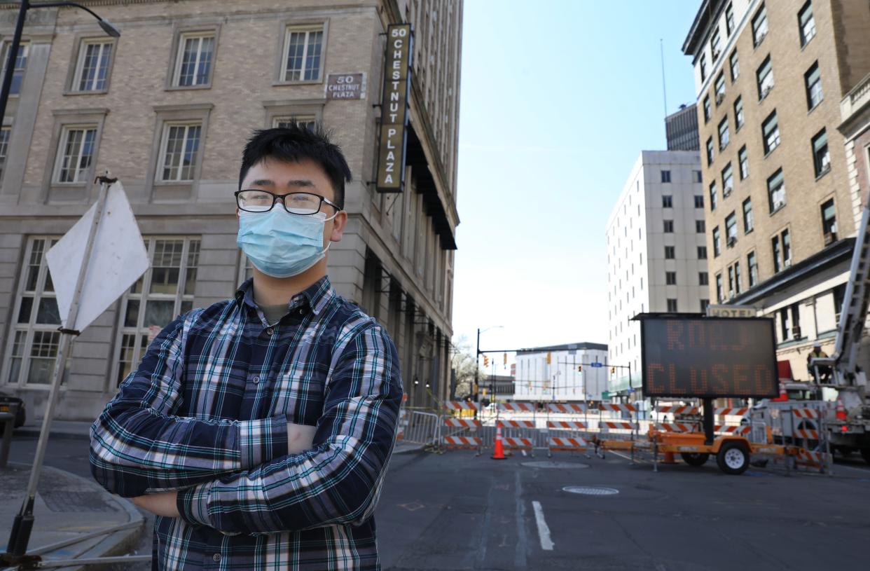 Yunzhi Yan stands outside his Chinese restaurant, Seasons' Noodle, at 50 Chestnut Street in downtown Rochester Friday, April 29, 2022. Yan has been unable to open his restaurant for the past week, since the partial collapse of siding panels on a long-vacant former hotel building on the next block.