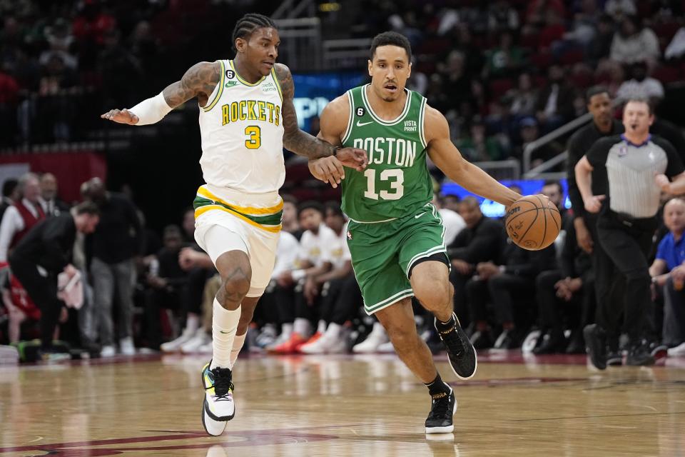 Boston Celtics' Malcolm Brogdon (13) brings the ball up the court as Houston Rockets' Kevin Porter Jr. (3) defends during the first half of an NBA basketball game Monday, March 13, 2023, in Houston. (AP Photo/David J. Phillip)