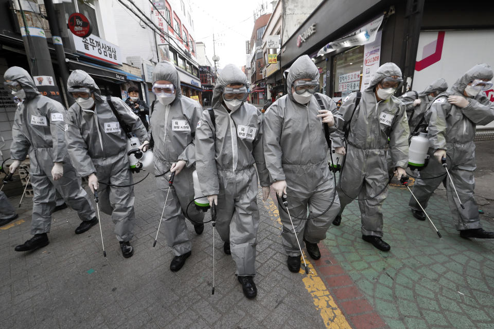Army soldiers wearing protective suits spray disinfectant as a precaution against the new coronavirus at a shopping street in Seoul, South Korea, Wednesday, March 4, 2020. The coronavirus epidemic shifted increasingly westward toward the Middle East, Europe and the United States on Tuesday, with governments taking emergency steps to ease shortages of masks and other supplies for front-line doctors and nurses. (AP Photo/Ahn Young-joon)