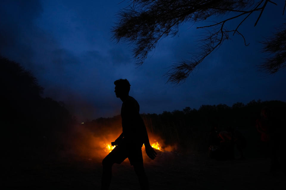 A Venezuelan migrant walks past garbage burning on a bank of the Rio Grande in Matamoros, Mexico, Friday, May 12, 2023, a day after pandemic-related asylum restrictions called Title 42 were lifted. (AP Photo/Fernando Llano)