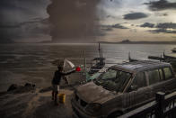 In this image released by World Press Photo, Thursday April 15, 2021, by Ezra Acayan for Getty Images, part of a series titled Taal Volcano Eruption, which won second prize in the Nature Stories category, shows A resident of Talisay in Batangas washes down a car, which is covered in volcanic ash mixed with rain, as Taal Volcano erupts, Batangas, Philippines, on Jan. 12, 2020. (Ezra Acayan for Getty Images, World Press Photo via AP)