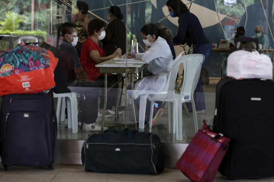 Elderly people wait to have a rapid COVID-19 test at the Brasilia Palace Hotel where they have been offered a safe space for self-isolation if they test negative, in Brasilia, Brazil, Thursday, April 23, 2020. The government began to receive seniors aged 60 and older and considered to be of low income into the “Hotelaria Solidaria” program, which aims to provide safe spaces for the elderly and will allow for physical distancing among them as a measure against the spread of new coronavirus. (AP Photo/Eraldo Peres)