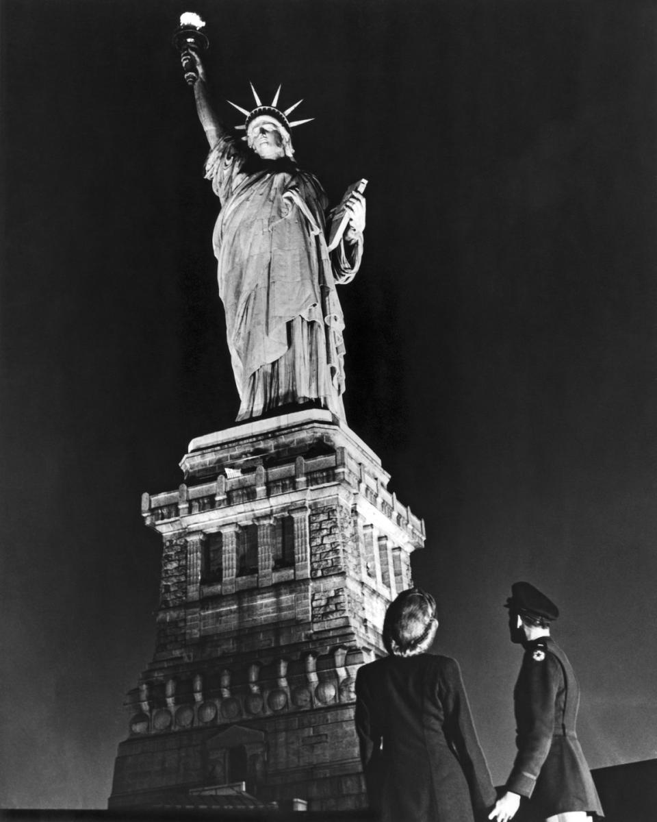 <p>A soldier and his companion steer away from V-E Day hoopla to gaze upon the Statue of Liberty. V-E Day marked the first time the Green Goddess was illuminated, except for a brief period on D-Day, since the Pearl Harbor attack.</p>