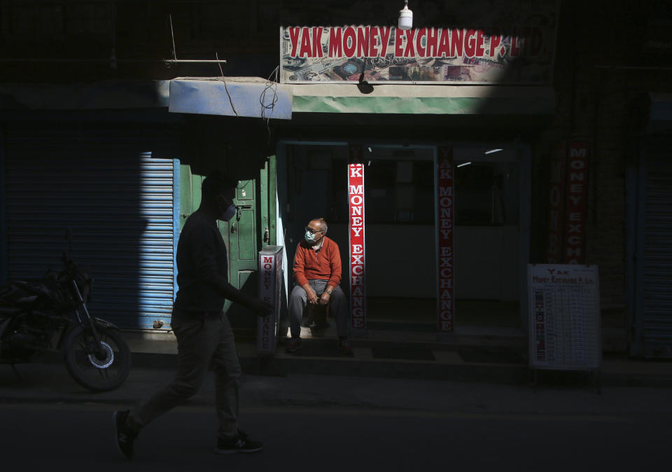 A Nepalese man waits for customers at his money exchange at Thamel, a touristic hub in Kathmandu, Nepal, Monday, Nov. 2, 2020. Nepal has reopened its peaks and trails for foreign adventurers in hopes of providing much needed income for hundreds of thousands of guides, porters and workers who have been unemployed for months because of the pandemic. For now the reopening will come with restrictions and mainly be limited to those seeking to to climb or trek its famous peaks. (AP Photo/Niranjan Shrestha)