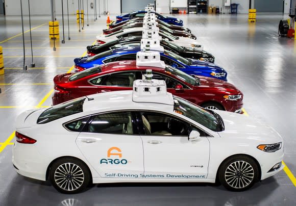 A row of Ford Fusion Hybrid sedans with "Argo AI" logos and visible self-driving sensor hardware