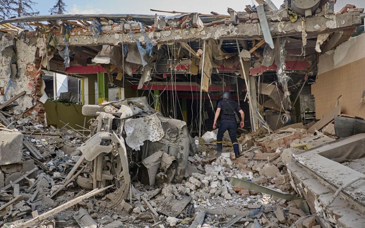 Ukrainian policemen work at the site of a glide bomb attack on a school in Kharkiv on June 23