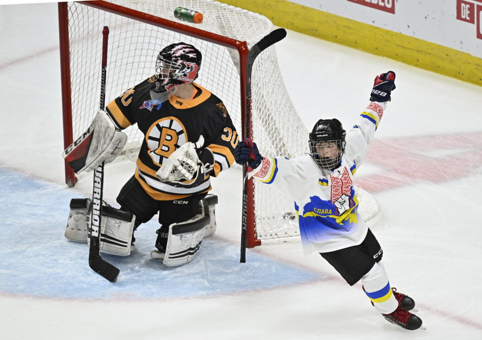 Ukraine peewee team's Ivan Bilozerov, right, celebrates his team‚'s winning goal against Boston Junior Bruins goalie James Boccuzzi during an international peewee hockey tournament, Saturday, Feb. 11, 2023, in Quebec City. (Jacques Boissinot/The Canadian Press via AP)