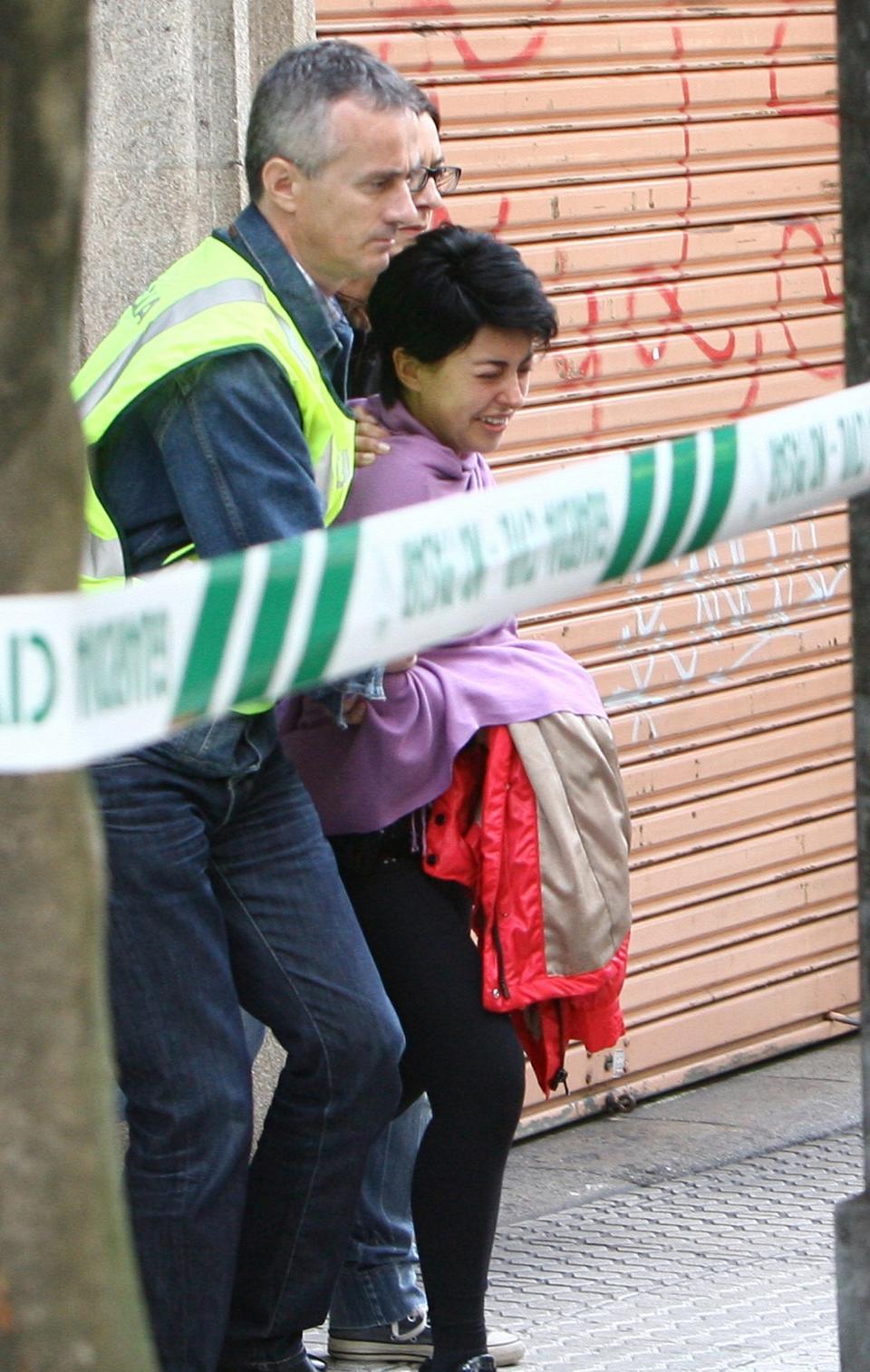 Authorities usher Rosario Porto out of a building.