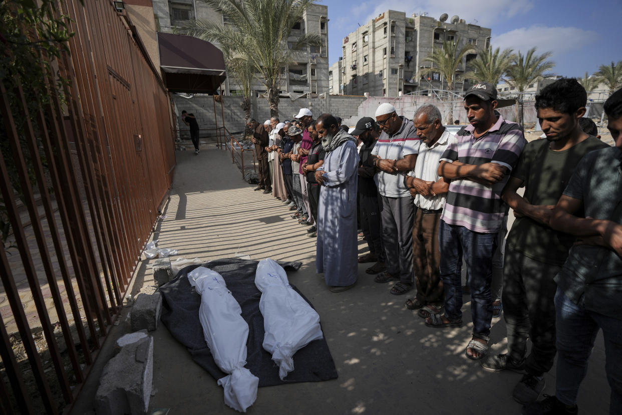 Mourners pray over the covered bodies of Palestinians who were killed in an Israeli airstrike on a crowded tent camp housing Palestinians displaced by the war in the Muwasi, outside the hospital morgue in Deir al-Balah, Gaza Strip, Tuesday, Sept. 10, 2024. (AP Photo/Abdel Kareem Hana)