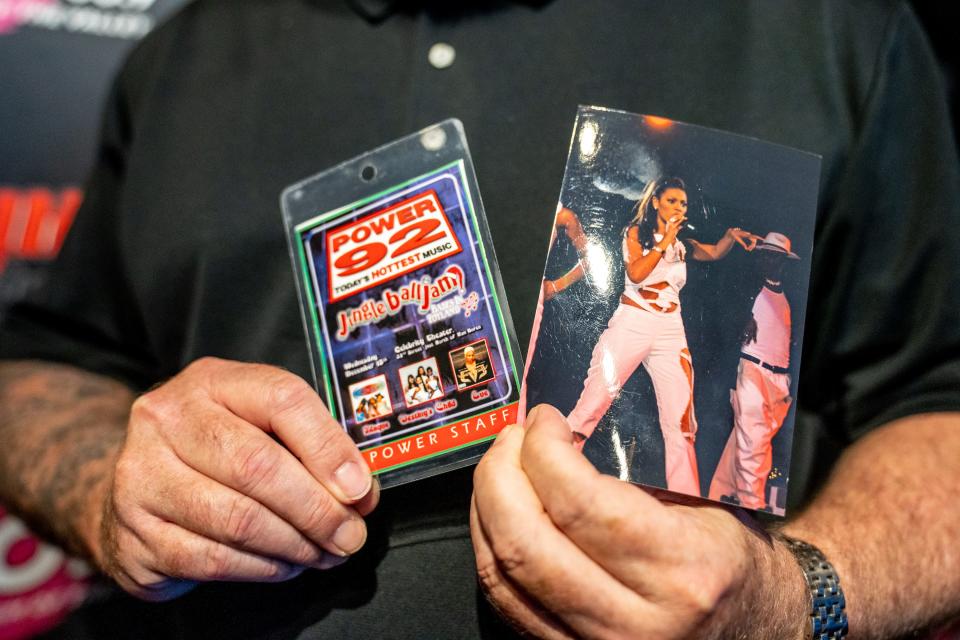 Charlie Huero, the assistant program director and afternoon host at HOT 97.5 & 103.9, poses for a portrait as he holds a 1999 staff credential and photograph of a Beyoncé and Destiny's Child performance at the Celebrity Theatre, at the radio station in Phoenix on Aug. 15, 2023.