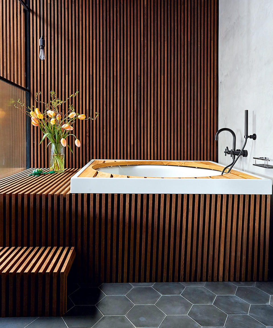 wood panelled bathroom with tub and black tiles
