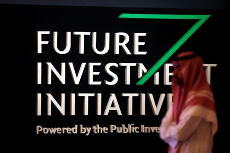 FILE PHOTO: A Saudi man walks past the sign of the Future Investment Initiative during the last day of the investment conference in Riyadh