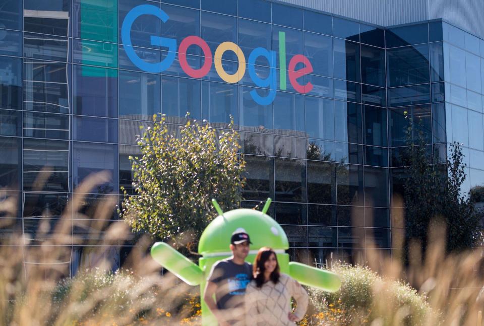 People pose for a picture near a Google sign and Android statue at the Googleplex in Menlo Park, California: JOSH EDELSON/AFP via Getty Images