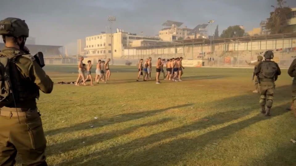 A still from a video appears to show Palestinian men and at least two children detained and stripped by the Israel Defense Forces (IDF) in a stadium in northern Gaza. - Yosee Gamzoo Letova