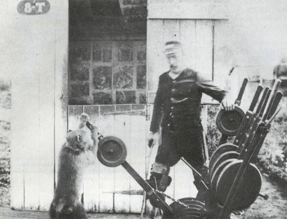 A baboon standing next to a man in a uniform and pushing a handle down