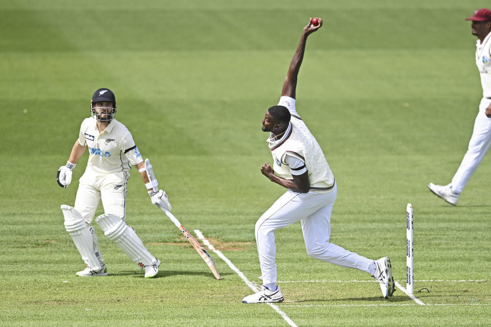 The West Indies' Jason Holder bowls as New Zealand's Kane Williamson, left, watches during play on day one of the first cricket test against New Zealand in Hamilton, New Zealand, Thursday, Dec. 3, 2020. (Andrew Cornaga/Photosport via AP)