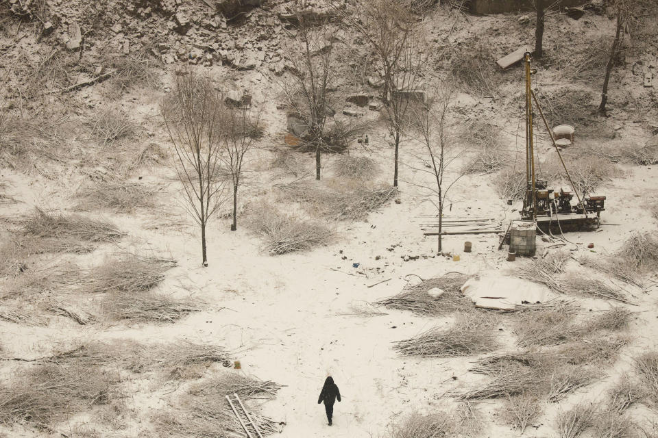 A man walks through the snow-covered surface of a work site in Beijing on Monday, Dec. 16, 2019. (AP Photo/Ng Han Guan)