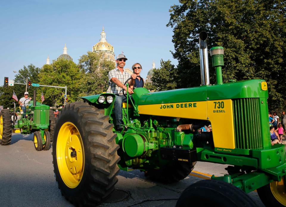 Members of the Central Iowa Tractor Club roll their John Deere along the parade route during the Iowa State Fair parade in Des Moines on Aug. 11, 2021.