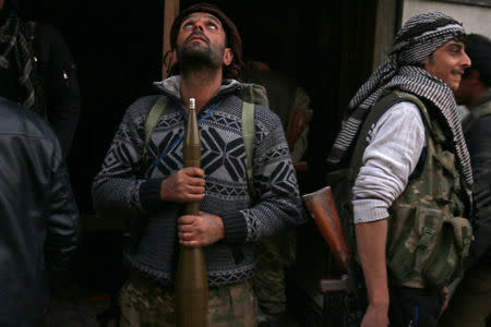 Rebel fighters carry their weapons as they pose in a rebel-held area of Aleppo, Syria. REUTERS/Abdalrhman Ismail