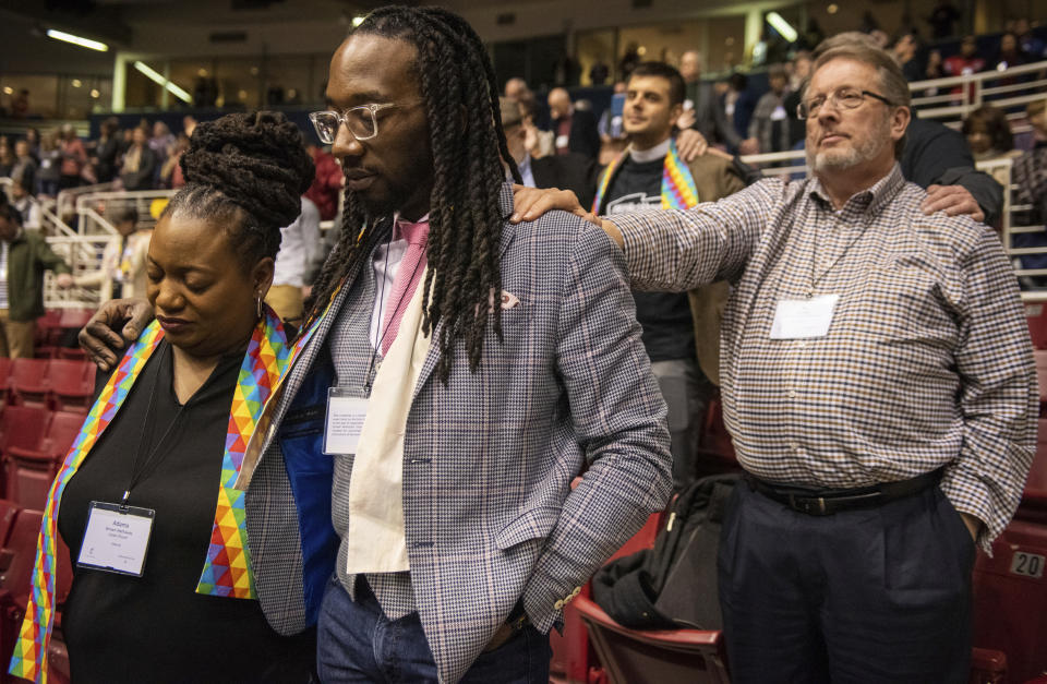 Adama Brown-Hathasway, left, The Rev. Dr. Jay Williams, both from Boston, and Ric Holladay of Kentucky join in prayer during the 2019 Special Session of the General Conference of The United Methodist Church in St. Louis, Mo., Tuesday, Feb. 26, 2019. America's second-largest Protestant denomination faces a likely fracture as delegates at the crucial meeting move to strengthen bans on same-sex marriage and ordination of LGBT clergy. (AP Photo/Sid Hastings)