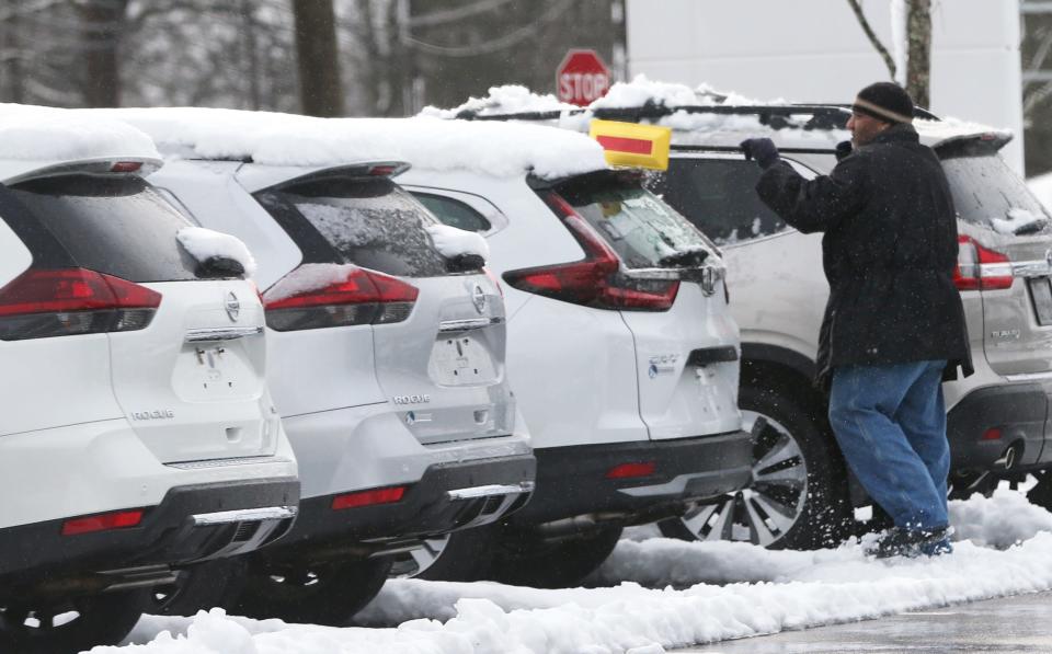 Following a wintery mix storm which still has Seacoast residents without power, a worker at a car dealership begins brushing the reminants of the storm away April 5, 2024.