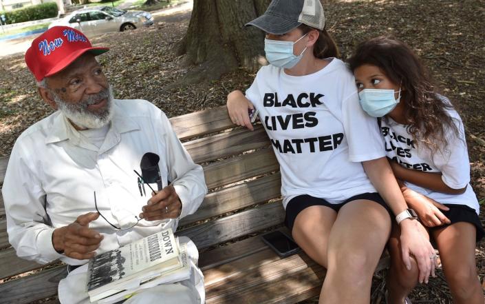 Civil Rights Leader James Meredith sits on a park bench in Smith Park in Jackson, Miss., with Keri Herrington and her niece Eriyuanna Woods - AP