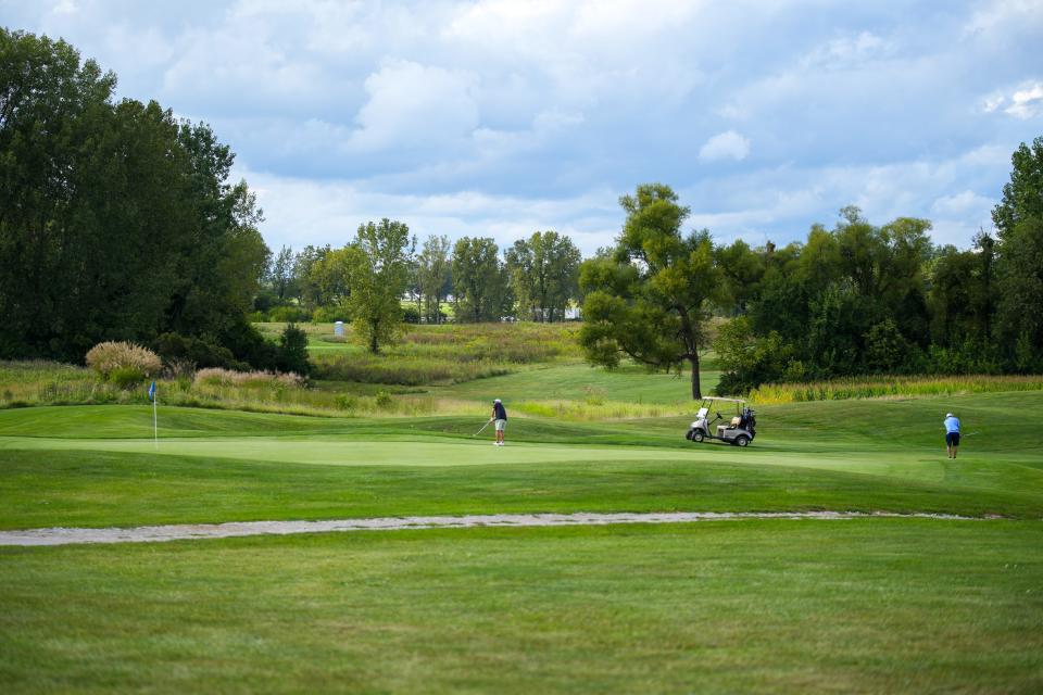 Two players putt on the 18th hole at National Golf Links.