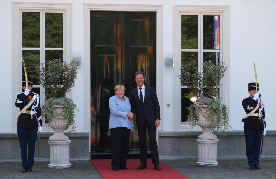 Dutch Prime Minister Mark Rutte, right, poses with German Chancellor Angela Merkel, at the entrance to his official residence in The Hague, Netherlands, Thursday Aug. 22, 2019. Merkel and key Cabinet ministers are meeting their Dutch counterparts Thursday to discuss ways of tackling climate change together, as Germany is set to miss its emissions goals for 2020 by a wide margin.(AP Photo/Mike Corder)