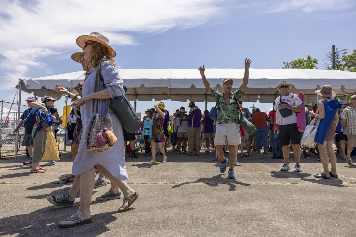 After finally getting past the gate people raise their arms in excitement at the New Orleans Jazz & Heritage Festival on Friday.