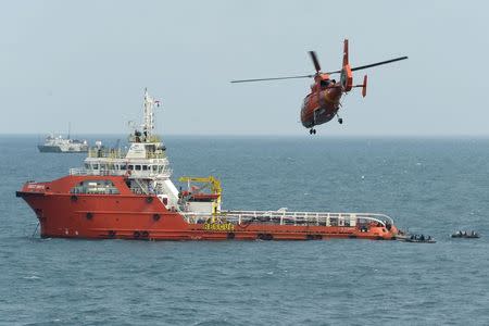 An Indonesian rescue helicopter flies over Crest Onyx ship as divers (R-in rubber boats) conduct operations to lift the tail of AirAsia flight QZ8501 in the Java Sea January 9, 2015. REUTERS/Adek Berry/Pool