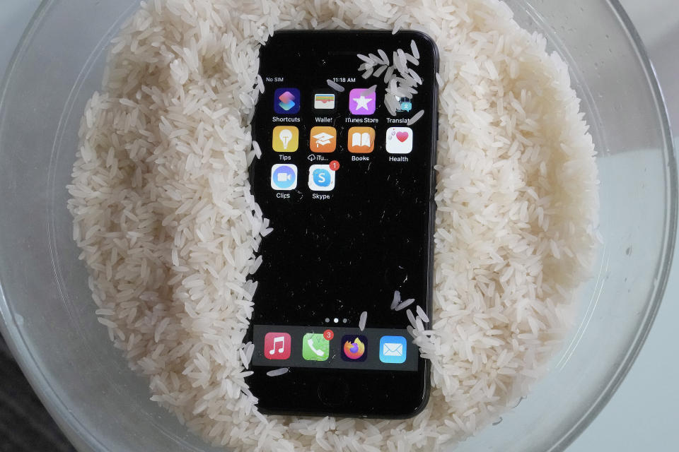 A view of a wet smartphone placed in a bowl of rice to dry, in London, Wednesday, Feb. 28, 2024. There's a lot of advice on the internet about what to do if you drop your phone in water, some of it conflicting. So what should you do then? Wipe as much moisture off as you can and leave it to dry. Don't use a hair dryer or put on a radiator. But whatever you do, don't dunk your device into a bowl of rice. (AP Photo/Frank Augstein)