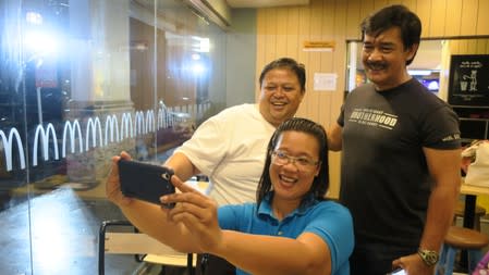 Sonny Parsons, leader of Filipino boyband Hagibis, poses for a photo with fans at a fastfood restaurant in Manila