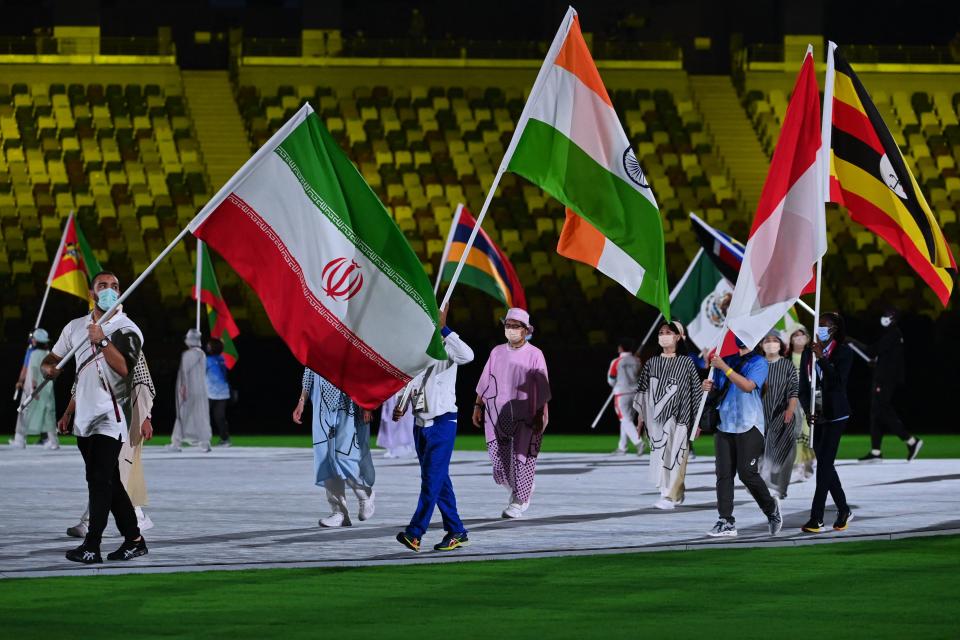 Iran's Amir Hossein Zare (L) and India's Bajrang Bajrang carry their national flags during the closing ceremony of the Tokyo 2020 Olympic Games, at the Olympic Stadium, in Tokyo, on August 8, 2021. (Photo by Adek BERRY / AFP) (Photo by ADEK BERRY/AFP via Getty Images)