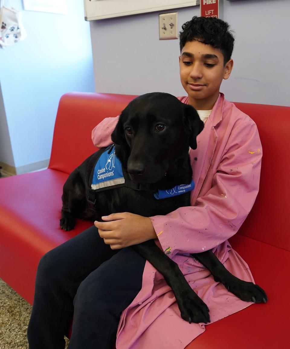 Fieldstone Middle School eighth-grader Chris Santano-Palanco sits with facility dog Maybie on Thursday, November 2023.